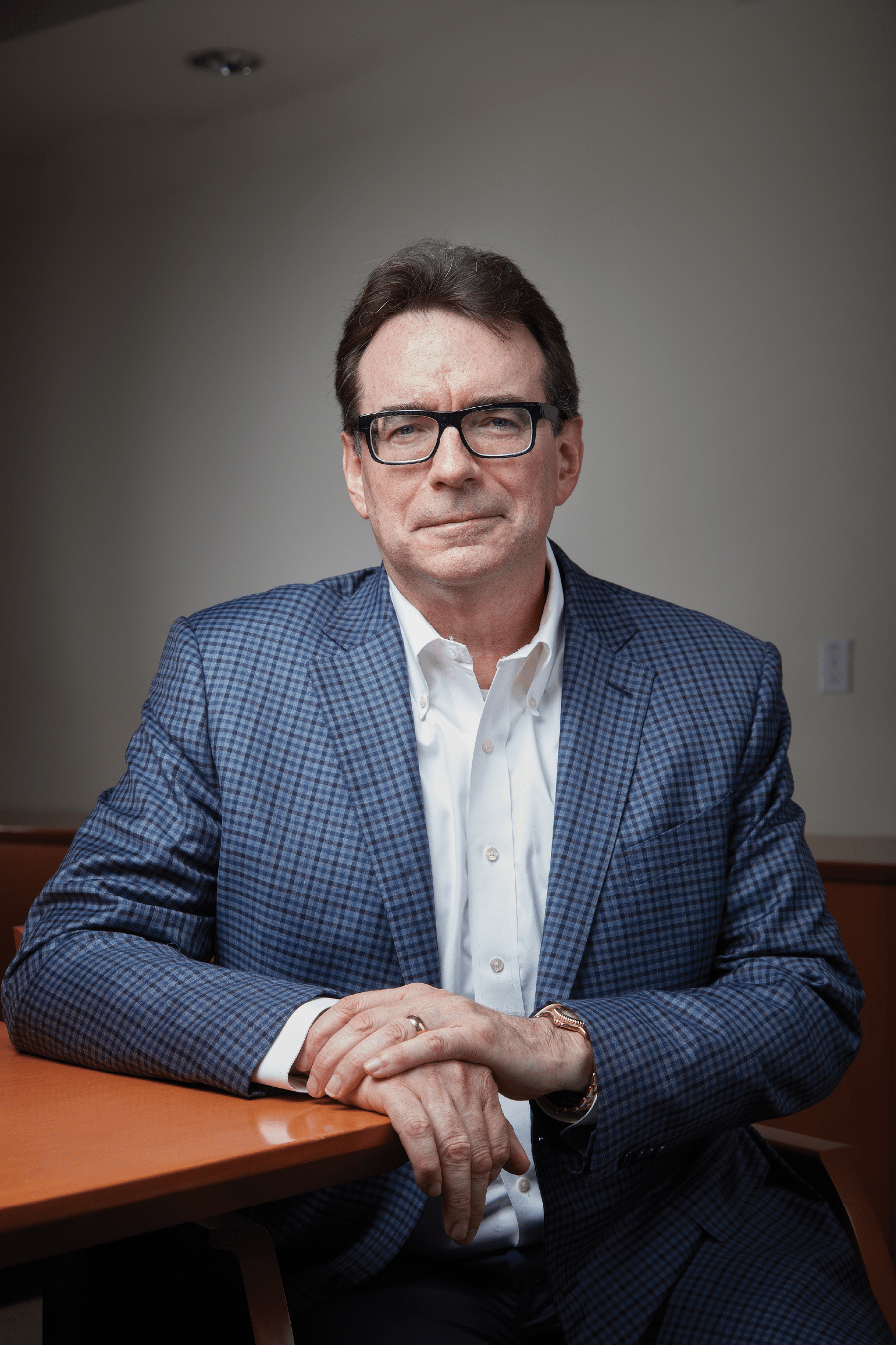 A man wearing a suit and glasses. Description generated by AI